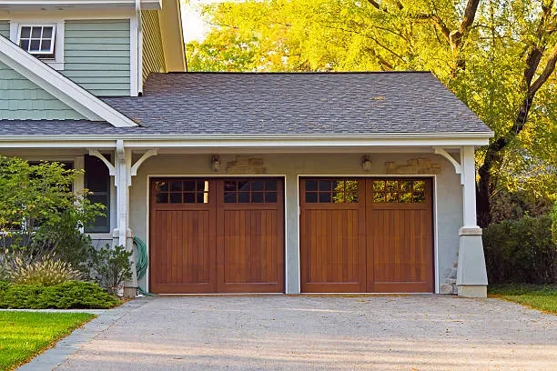 wooden garage doors with dark brown bricked roof outdoor view with yellow leaves on tree -repair garage door